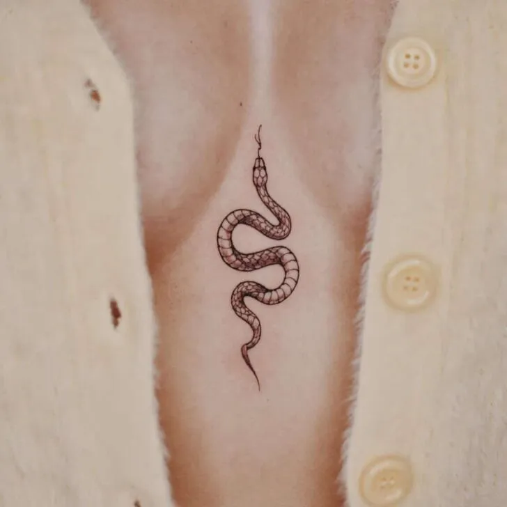 minimalist snake sternum tattoo